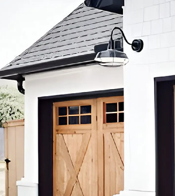 A white house with two wooden doors and a black roof.