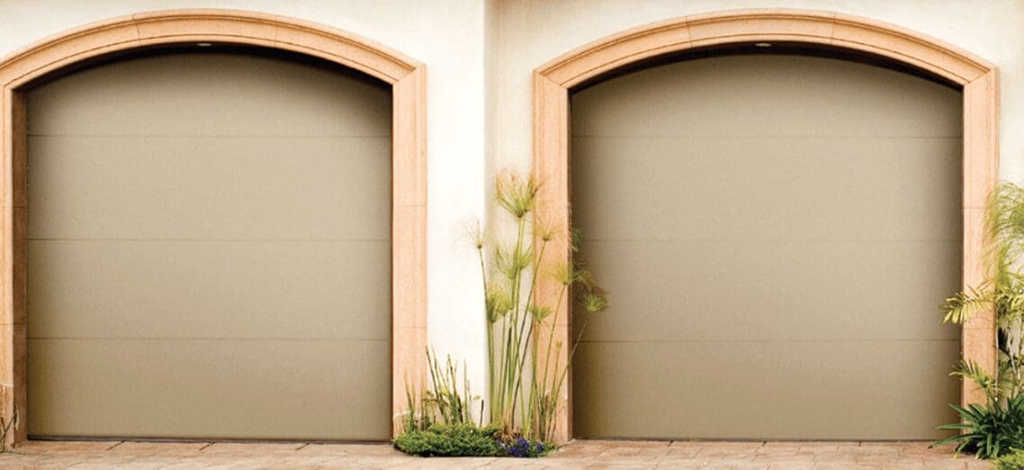 Two arched garage doors with plants in the center.