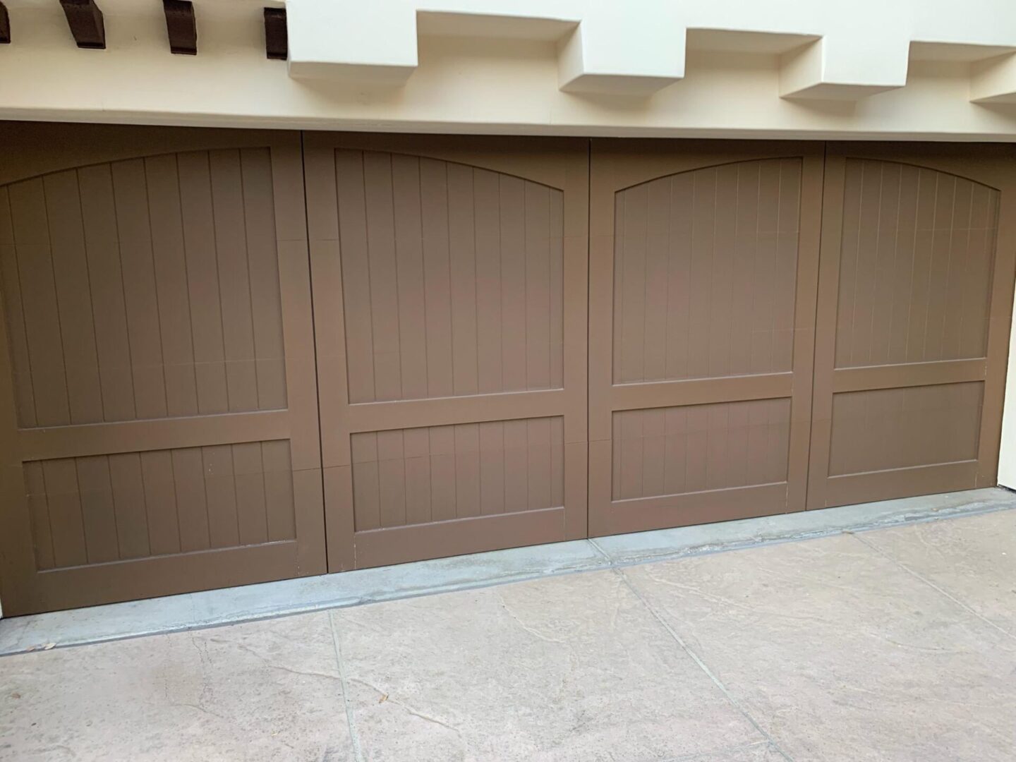 A tan garage door with white trim and a beige wall.