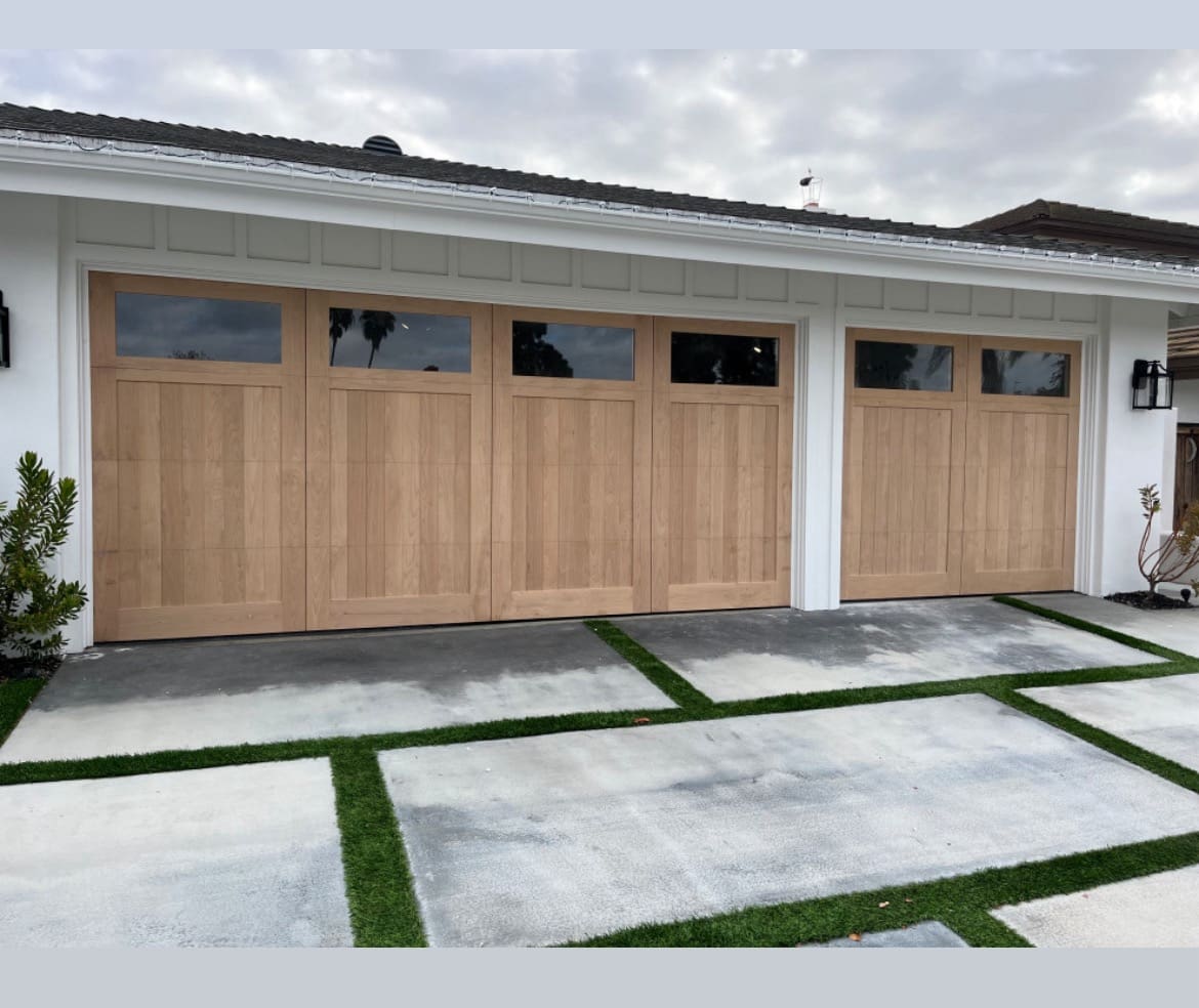 A garage with three wooden doors and two windows.