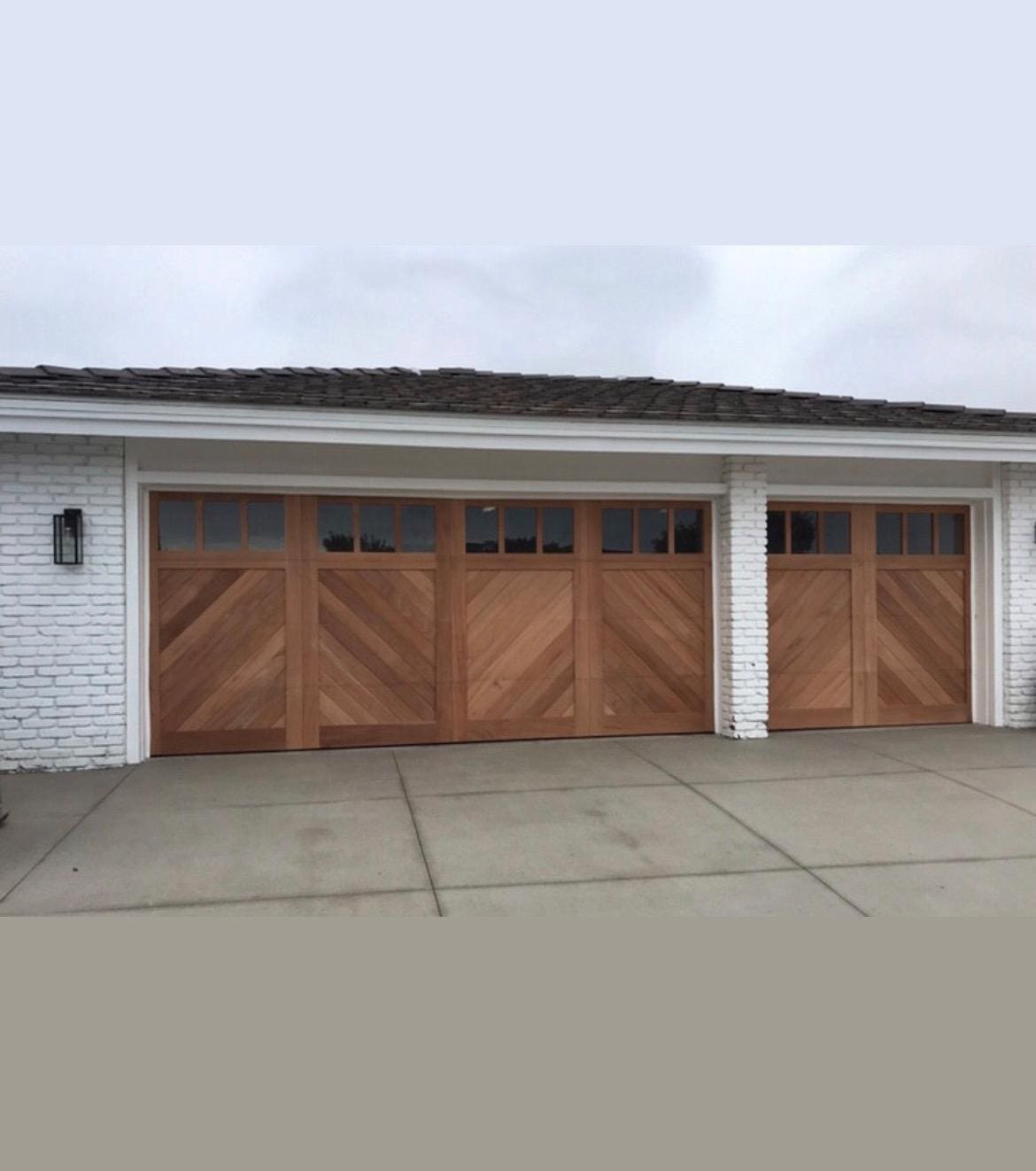 A white house with three wooden garage doors.