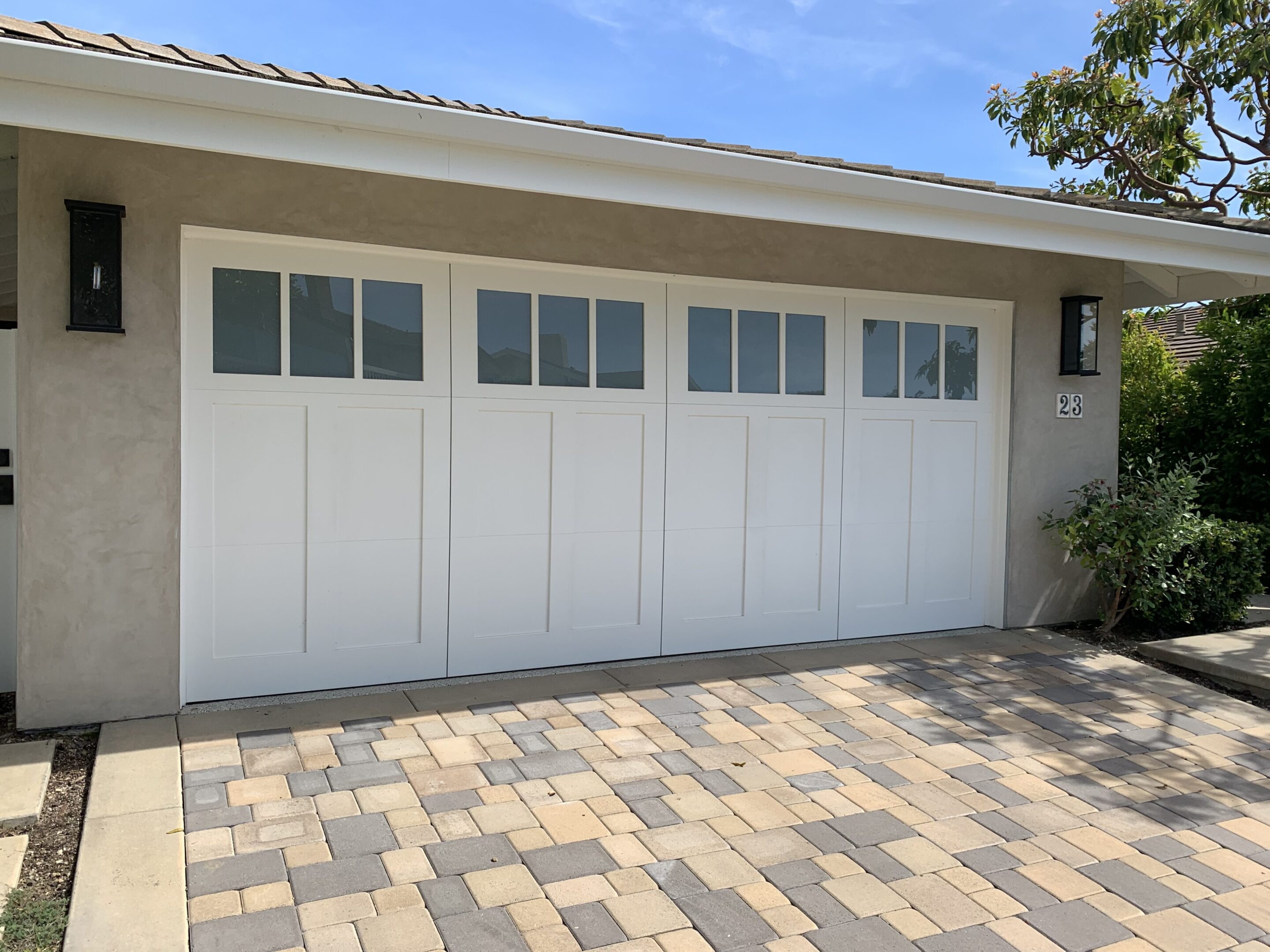 A white garage door sitting on top of a brick driveway.